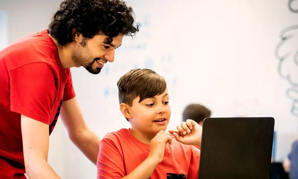 Un jeune et son formateur regarde le code d'un jeu vidéo