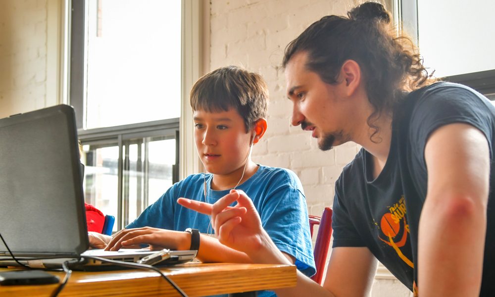 Un formateur explique à un élève de l'école Studio XP